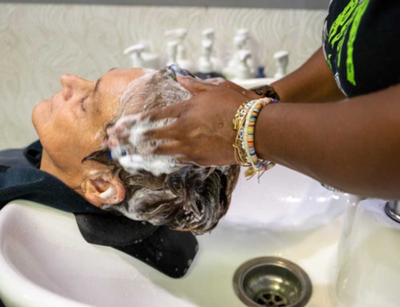 Person getting hair washed in a salon sink by a stylist.