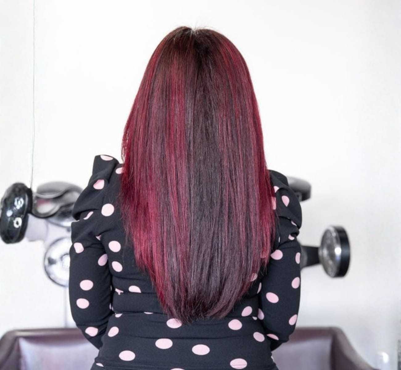 Red ombré hair on woman in black and pink polka dot dress, facing away.