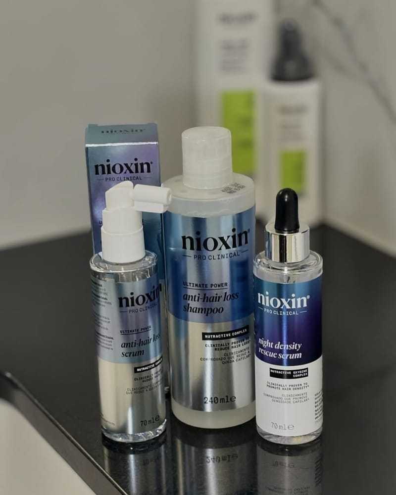 Nioxin haircare products on a bathroom counter: shampoo and two serums.
